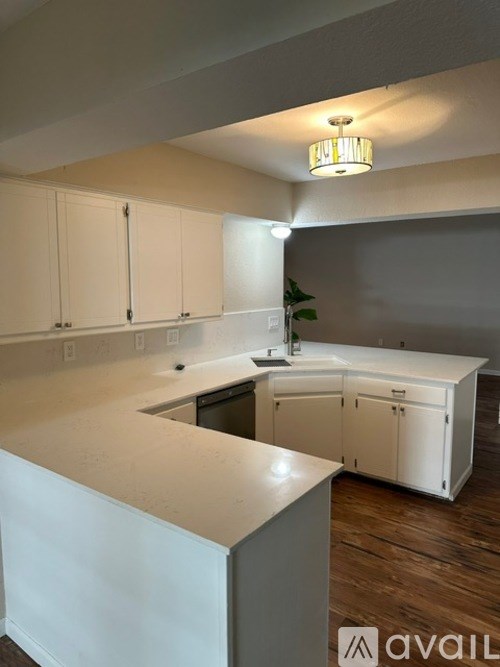 A kitchen with white cabinets and a wooden floor.