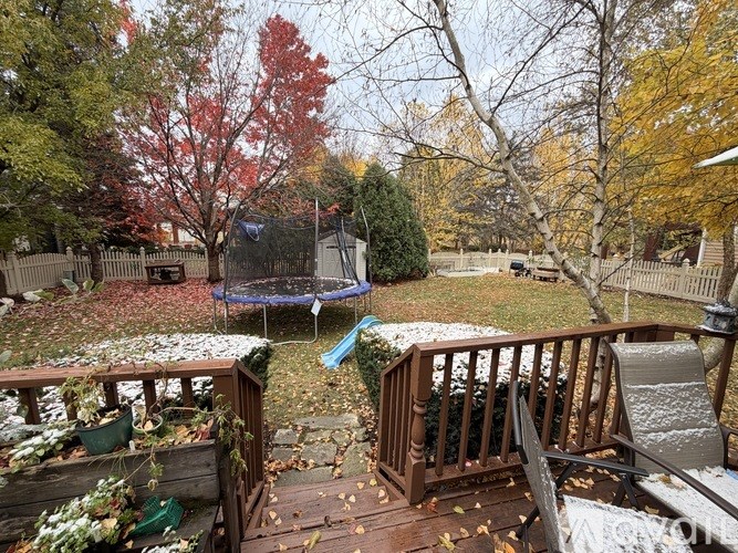 A backyard with a trampoline and a deck.