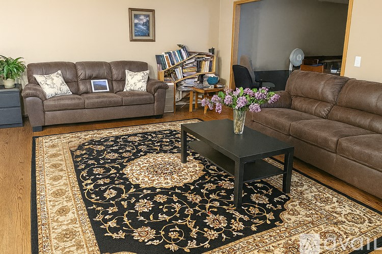 A living room with a brown couch, a coffee table, and a rug.