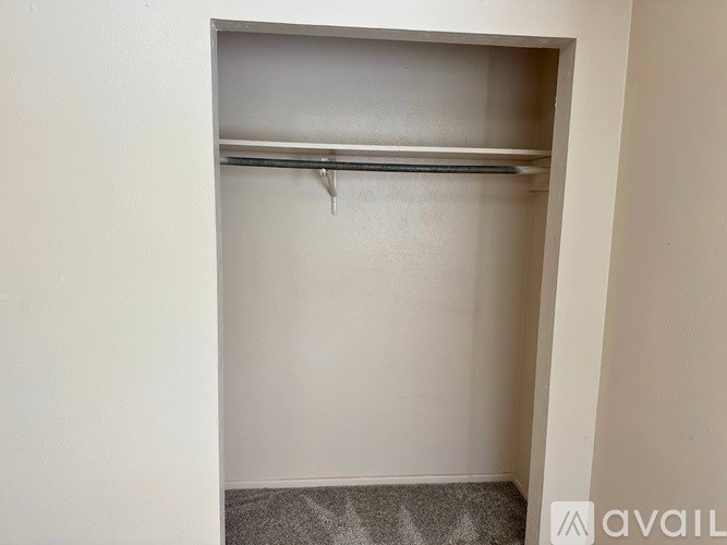 A small, empty closet with a single rod hanging from the ceiling.