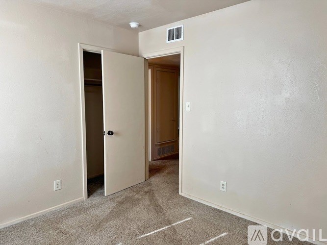 A room with a carpeted floor and two doors, one of which is open.