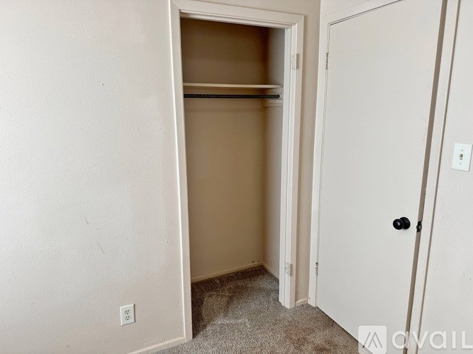 A white door is open to a small, empty room with a carpeted floor.