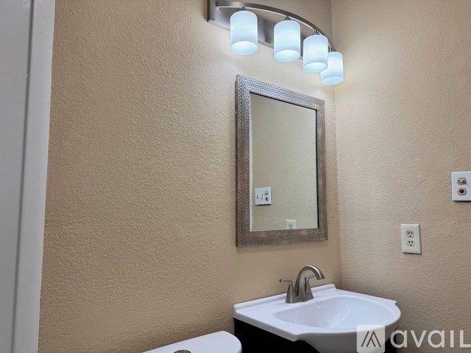 A bathroom with a sink, mirror, and light fixture.