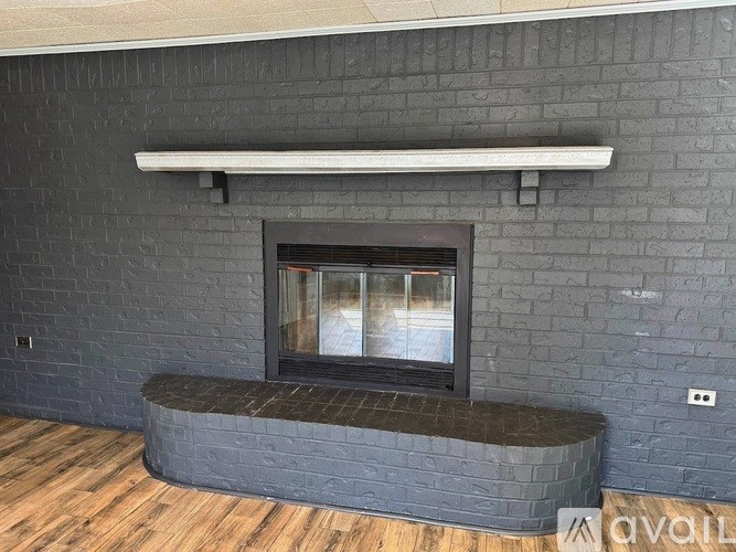 A modern fireplace with a grey brick wall and wooden floor.