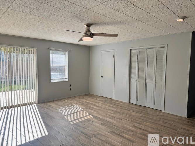 A room with a ceiling fan and wooden flooring.