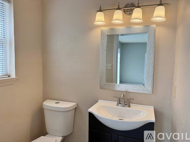 A bathroom with a toilet, sink, and mirror.