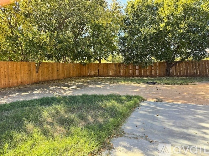 A backyard with a wooden fence and a grassy area.