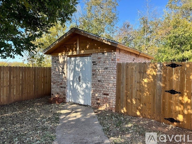 A small building with a white door is surrounded by a wooden fence.