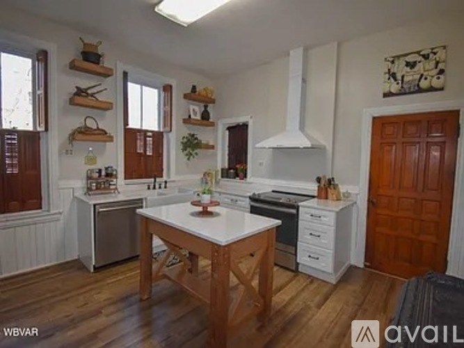 A kitchen with a white table and wooden floors.