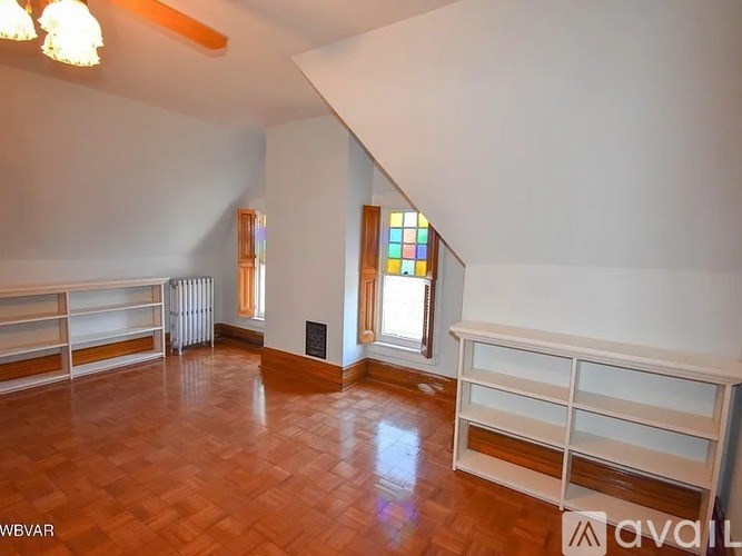 A room with wooden floors and white walls, featuring a stained glass window and a radiator.
