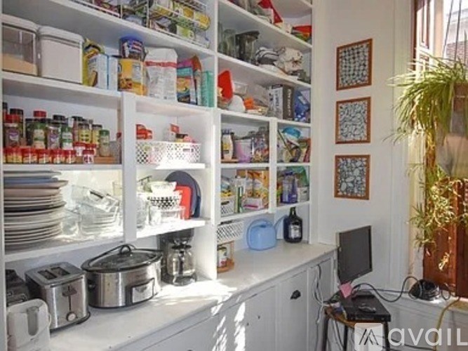 A kitchen with white cabinets and a variety of food items on the shelves.