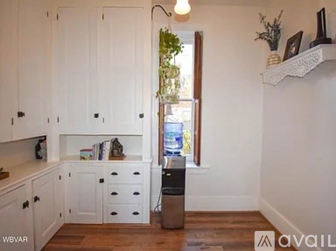A kitchen with white cabinets and a wooden floor.