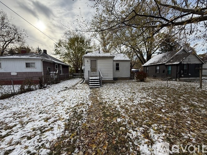 A snowy backyard with a small house and a shed.