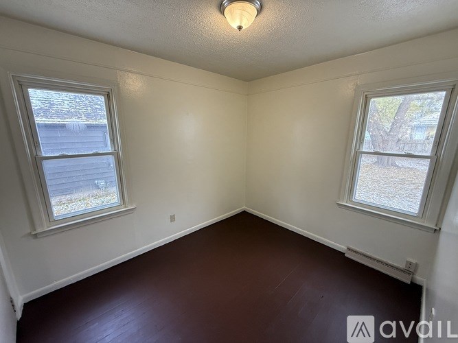 A room with two windows and a wooden floor.