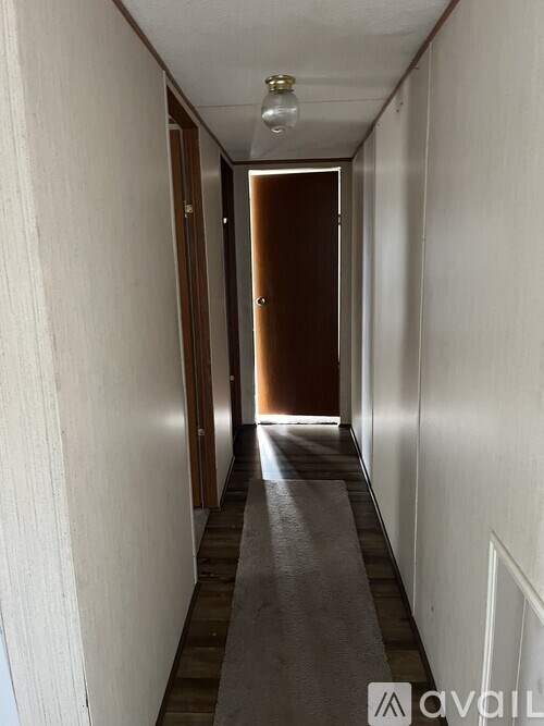 A long hallway with a brown door at the end.