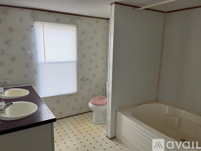 A bathroom with a tub, sink, and window.
