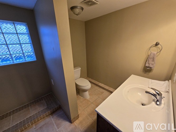 A bathroom with a toilet, sink, and a window.