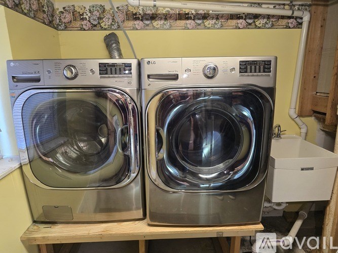 Two front loading washing machines on a wooden shelf.