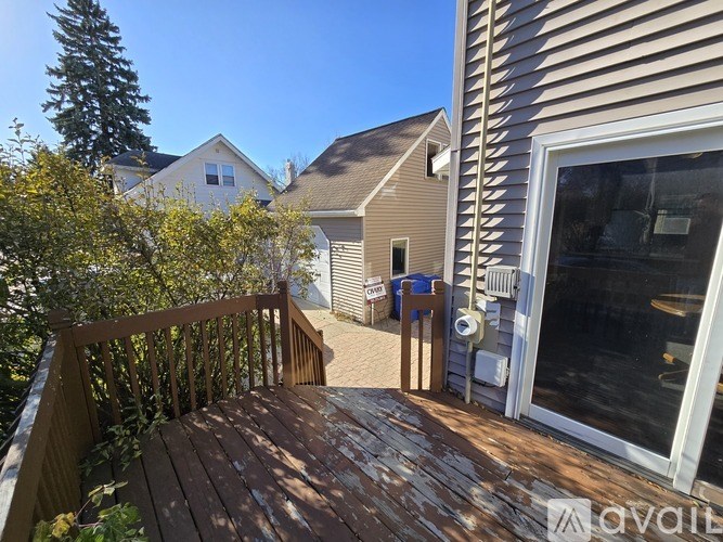 A wooden deck with a railing and a table is in front of a house.
