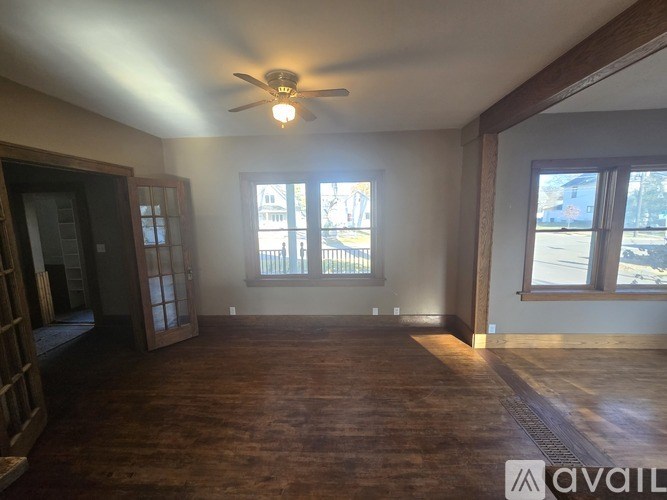 A room with a ceiling fan and two windows.