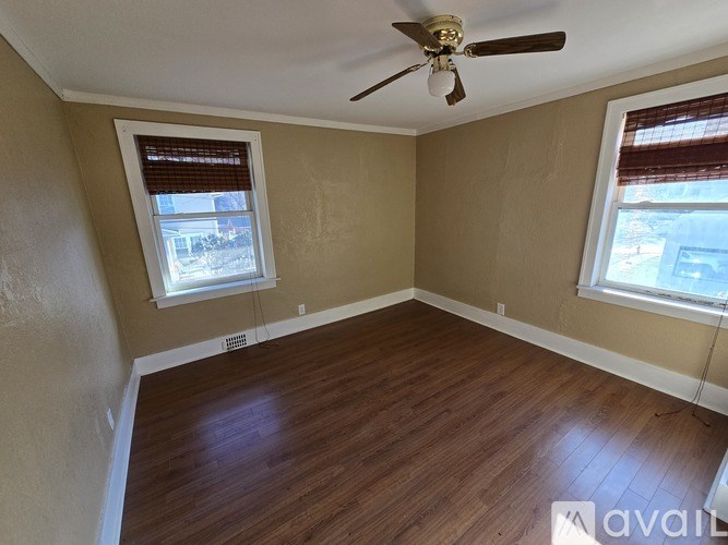 A room with wooden flooring and a ceiling fan.