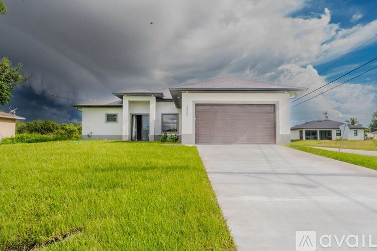 A house with a grey garage door is in front of a cloudy sky.