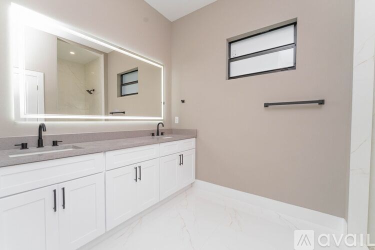 A bathroom with a marble countertop and white cabinets.