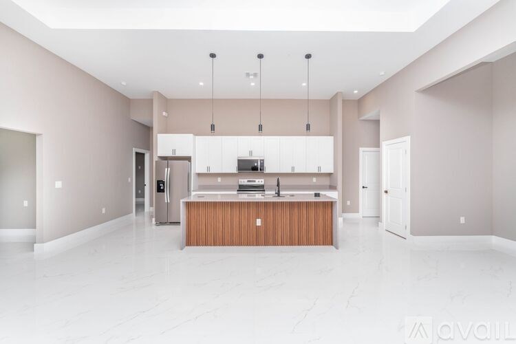 A modern kitchen with a central island and pendant lights.