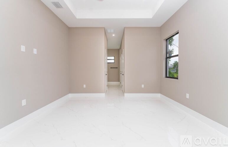 A spacious room with white flooring and beige walls.