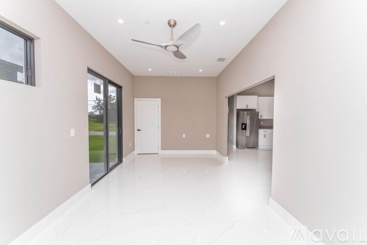 A spacious, empty room with a ceiling fan and a door leading to another room.