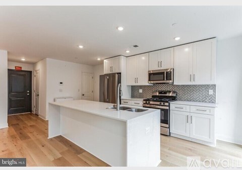 A kitchen with white cabinets and a wooden floor.