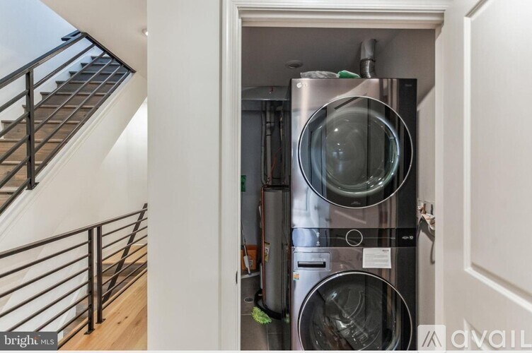 A stainless steel dishwasher and washing machine are installed in a narrow space under a staircase.