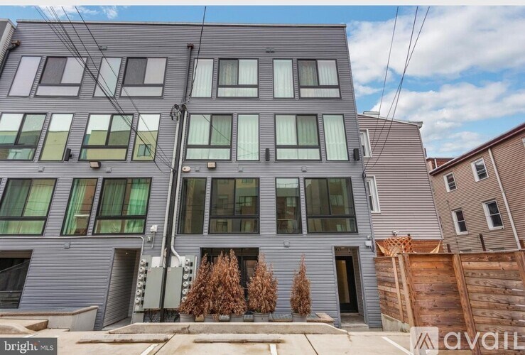 A modern two-story building with a grey facade and large windows is for sale.