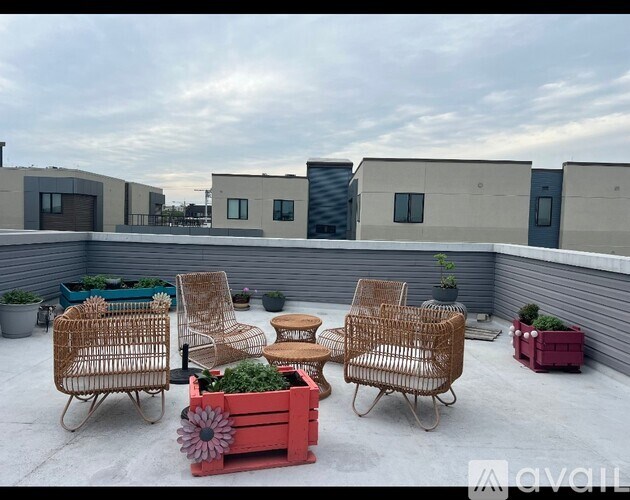 A patio with wicker chairs and a red planter box.