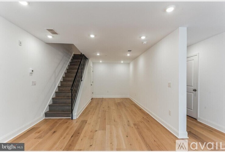 A spacious room with wooden floors and a staircase.