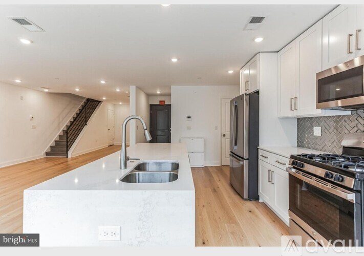 A modern kitchen with a stainless steel sink and refrigerator.