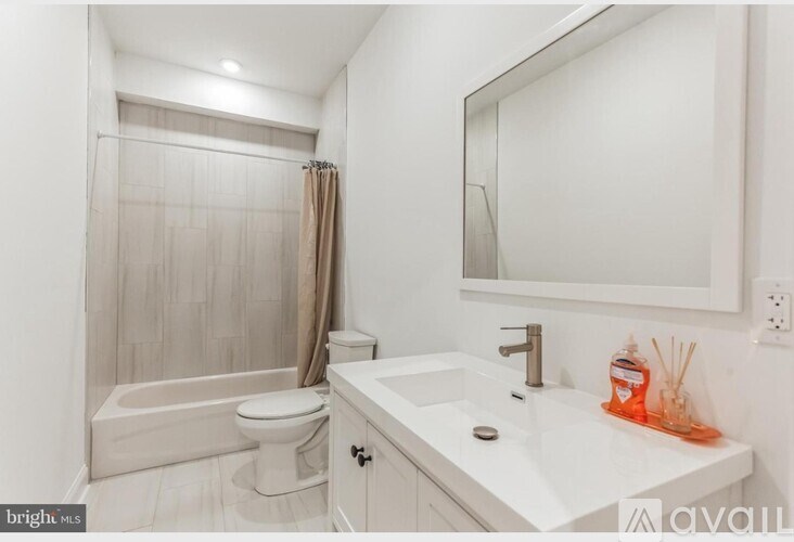 A white bathroom with a toilet, sink, and shower.