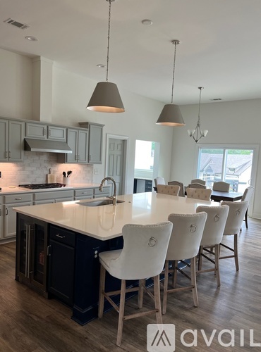 A modern kitchen with a large island and chairs.