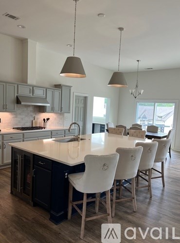 A modern kitchen with a large island and chairs.