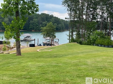 A grassy area with a lake and dock in the distance.