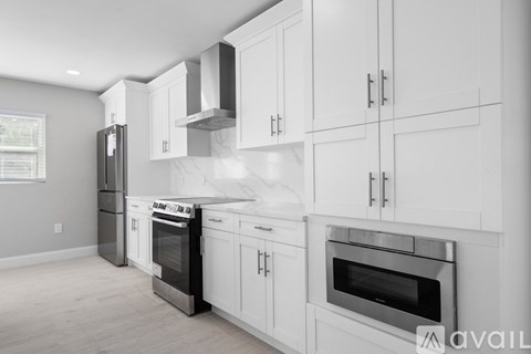 A modern kitchen with white cabinets and stainless steel appliances.