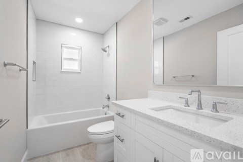 A white bathroom with a tub, toilet, and sink.
