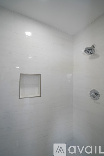 A shower head is mounted on a white tiled wall.
