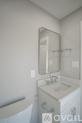 A bathroom with a white toilet, sink, and mirror.