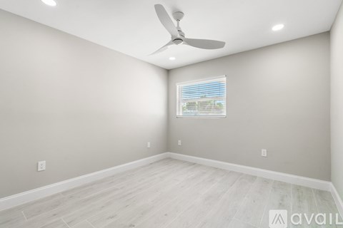 A room with a ceiling fan and a window with blinds.