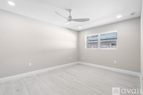 A room with a ceiling fan and a window with blinds.