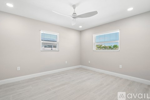 A room with a ceiling fan and two windows.