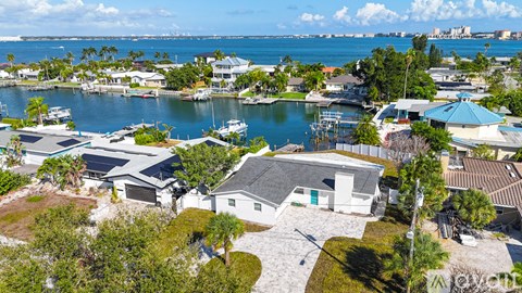 A house with a blue roof is surrounded by other houses and boats.