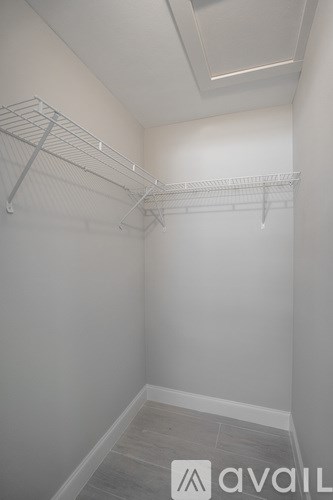 A walk-in closet with a white wall and a grey floor.