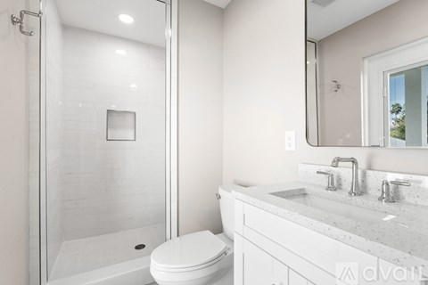 A white toilet sits next to a walk-in shower in a bathroom.